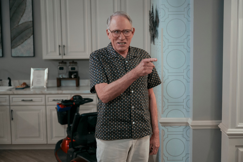 John Getz as Elliot stands in a kitchen pointing and smiling in Season 1 of 'A Man on the Inside'