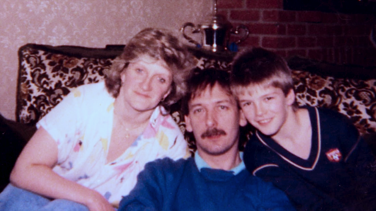 Sandra Georgina West, Ted Beckham, and David Beckham sitting together on the couch.