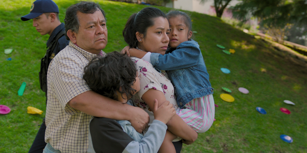 Silverio Palacios as Moncho and Shaní Lozano as Yolanda wear concerned expressions as they hug their children outside, with party accoutrement on the grassy hill behind them, in an image from the series ‘The Accident.’