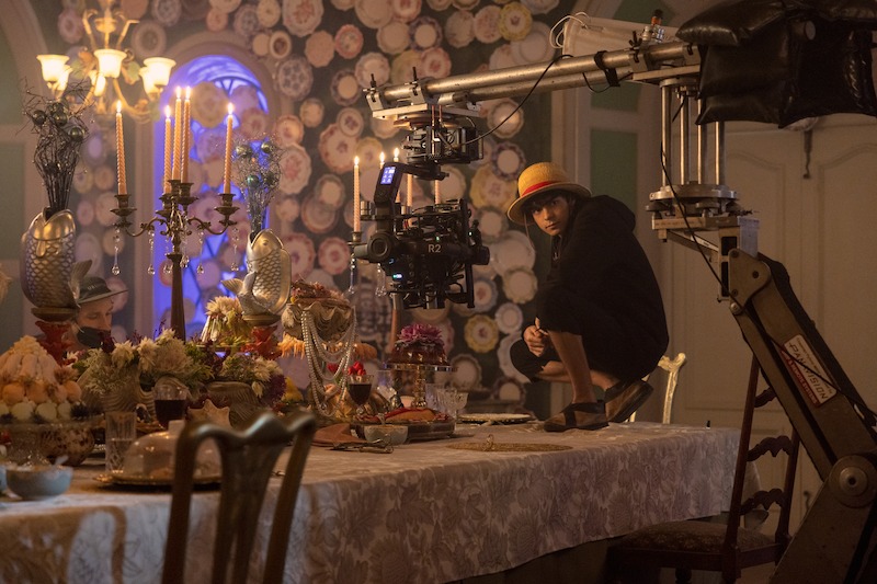 Iñaki Godoy as Monkey D. Luffy stands on a table full of food on the set of Season 1 of 'One Piece.'