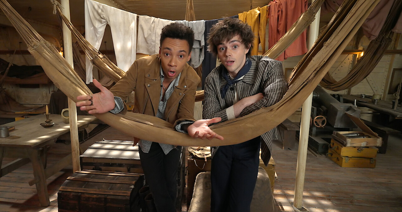 Kit Young and Jack Wolfe lean on a ship hammock as Jesper and Wylan