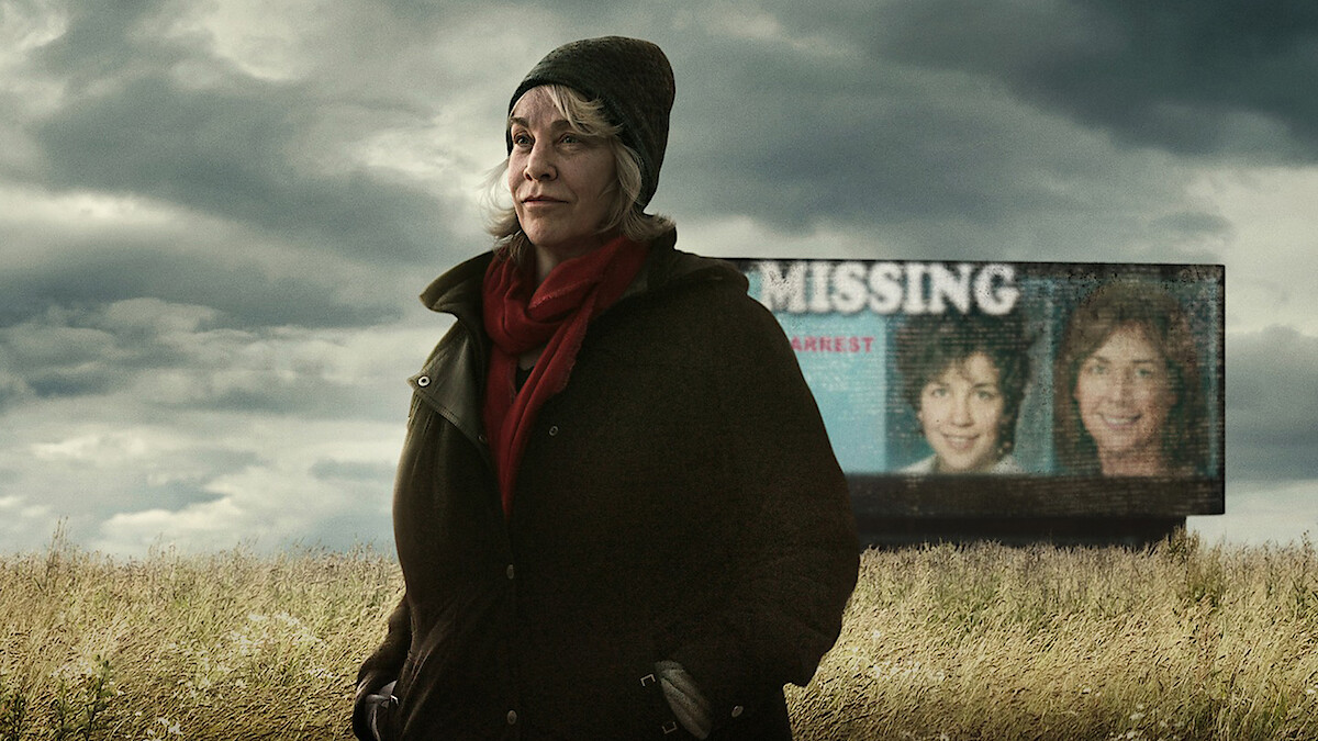 Cathy Terkanian standing in a field with a missing persons billboard in the background.