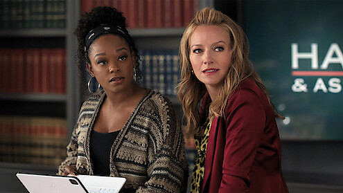 Two women standing together behind a desk.