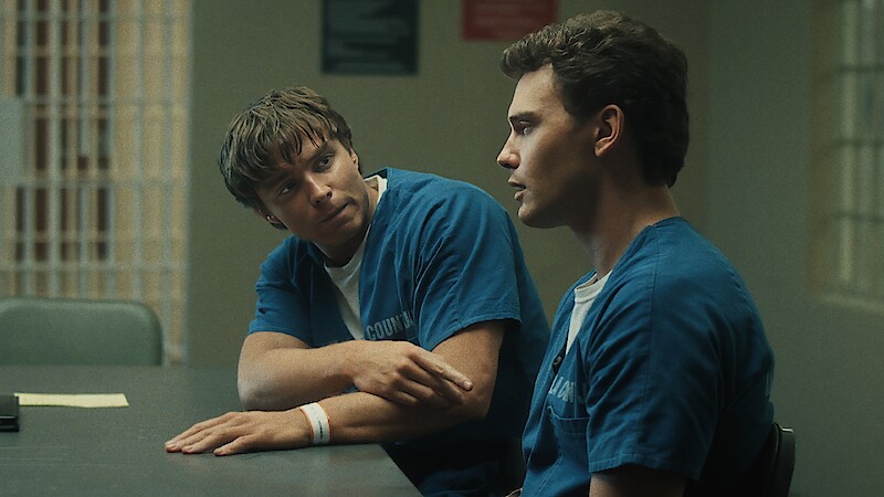 Two men in prison uniforms sitting at a table.