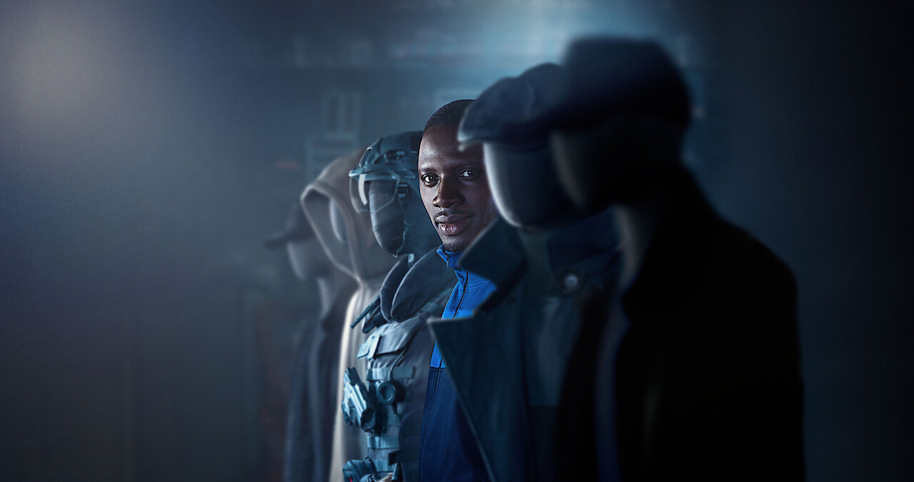 Omar Sy as Assane Diop stands in a row of mannequins wearing disguises in Season 3 of 'Lupin.'