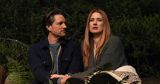Two people sitting down next to each other outside