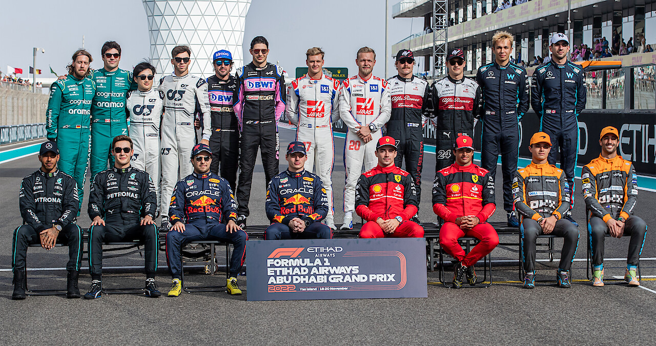 Formula 1 race car drivers pose for a photo with Abu Dhabi Grand Prix sign 