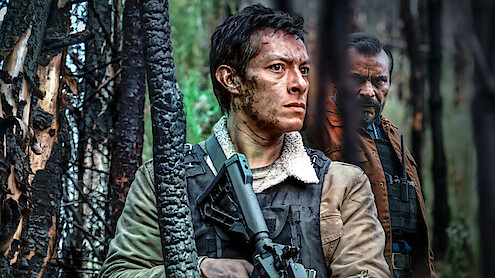  A man holds a gun while another man leers at him from behind
