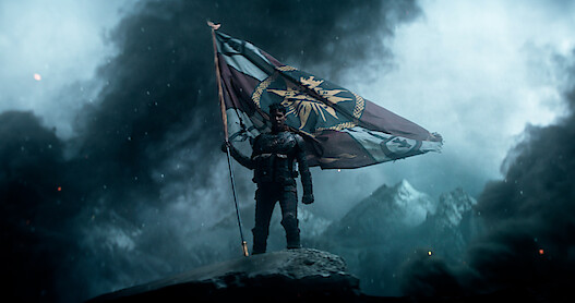 A person holding a flag surrounded by smoke 