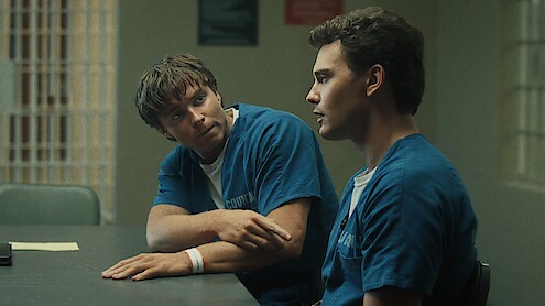 Two men in prison uniforms sitting at a table.