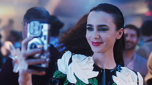 Lily Collins as Emily takes a picture with her phone in Season 4 of 'Emily in Paris'