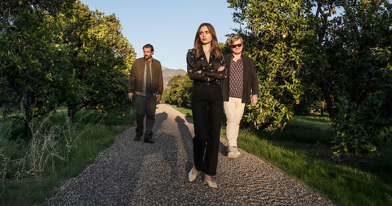 Lily Collins and others walking amid orange groves in the film 'Windfall'