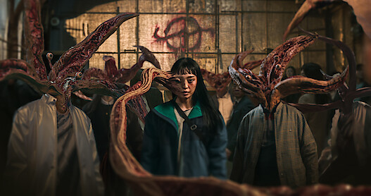 A tentacle-like appendage grows from a woman's head in Parasyte: The Grey