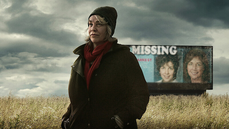 Cathy Terkanian standing in a field with a missing persons billboard in the background.
