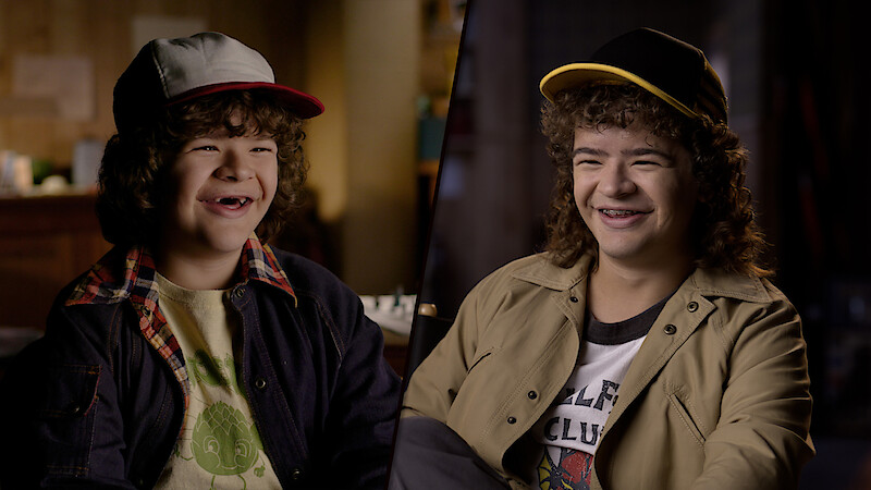 A split-screen image featuring a younger Gaten Matarazzo alongside an older teen version of him, both dressed in casual attire with baseball caps, smiling warmly in softly lit indoor settings.
