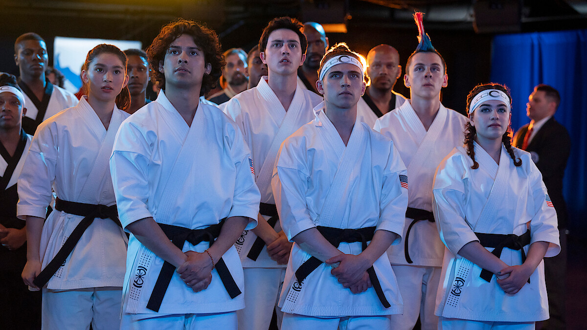 Xolo Maridueña as Miguel Diaz, Gianni DeCenzo as Demetri, and Jacob Bertrand as Eli 'Hawk' Moskowitz stand together in karate uniforms in Season 6 of ‘Cobra Kai’