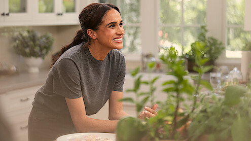 Meghan smiling in the kitchen with plants in the foreground.