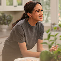 Meghan smiling in the kitchen with plants in the foreground.