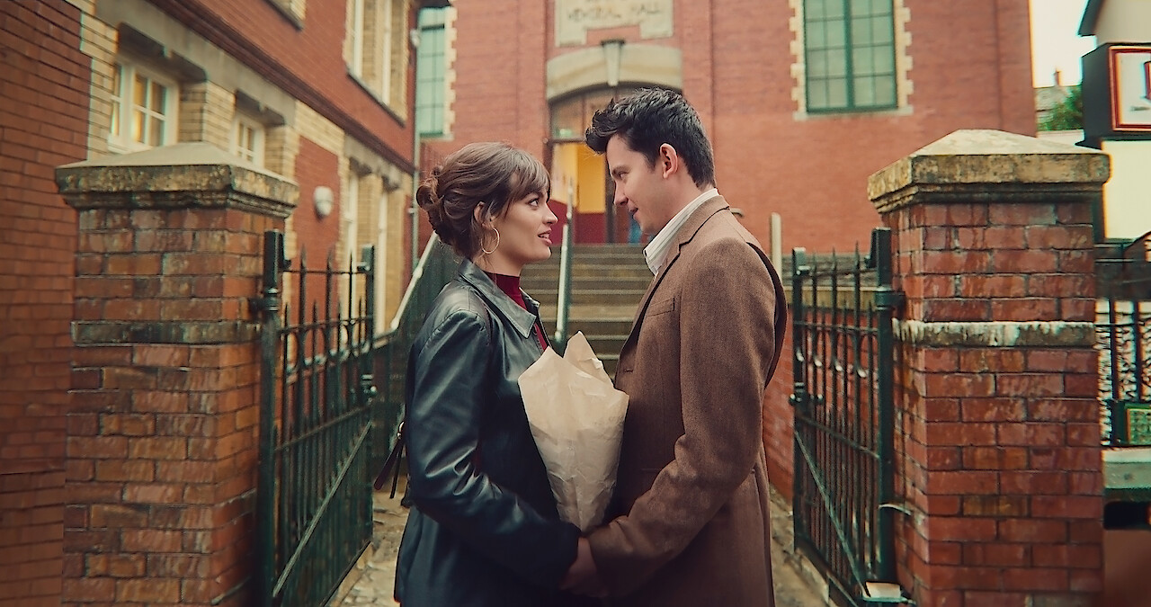 Emma Mackey as Maeve and Asa Butterfield as Otis stand facing each other and holding hands in Season 4 of 'Sex Education.'
