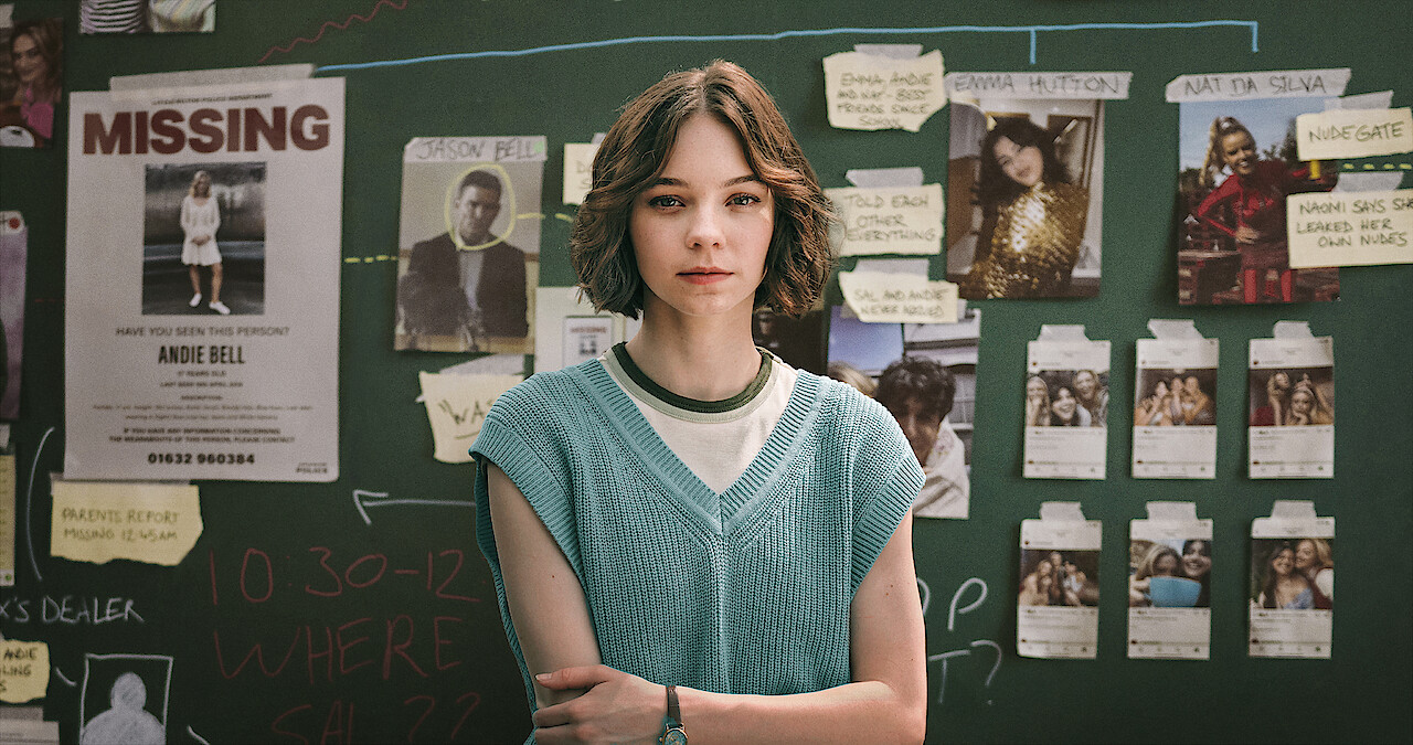 Emma Myers as Pip stands infront of a chalkboard covered in suspect photos and clue clippings in Season 1 of 'A Good Girl's Guide to Murder'