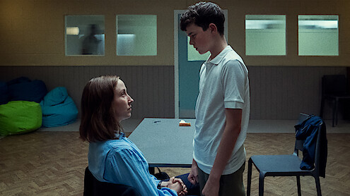  A woman sits in a chair with a teenage boy standing over her