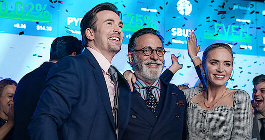 Chris Evans, Andy Garcia and Emily Blunt celebrate in a scene from 'Pain Hustlers.'