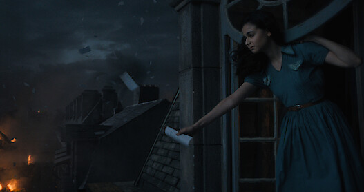 All the Light We Cannot See - a woman in a blue dress looking out on a burning city