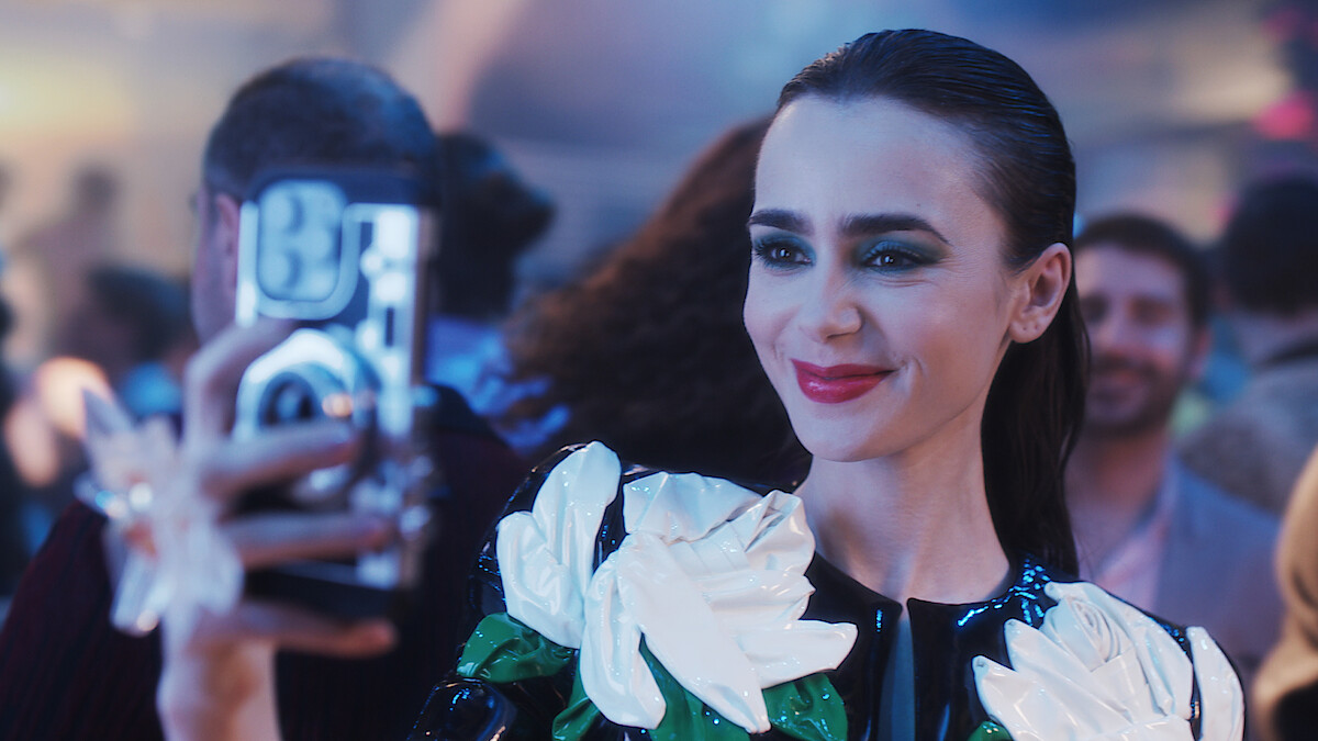 Lily Collins as Emily takes a picture with her phone in Season 4 of 'Emily in Paris'
