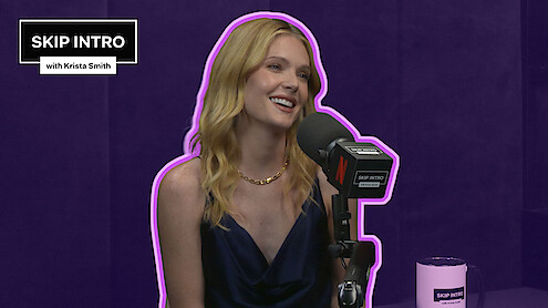 Meghann Fahy smiles and speaks into a “Skip Intro with Krista Smith” microphone against a purple background, with a matching “Skip Intro” mug on the table.