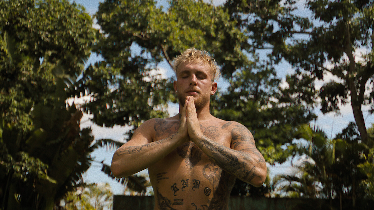 Jake Paul sitting shirtless with his hands clasped together. 