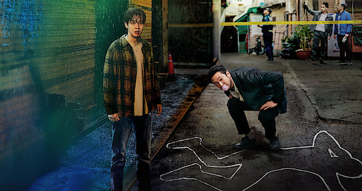 Choi Woo-shik as Lee Tang and Son Suk-ku as Jang Nan-gam stand together at a crime scene in Season 1 of 'A Killer Paradox'