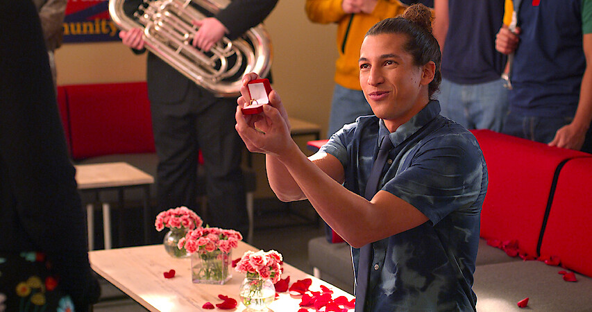 Benjamin Norris as Trent in Season 4 of Never Have I Ever, kneeling and holding an open ring box.