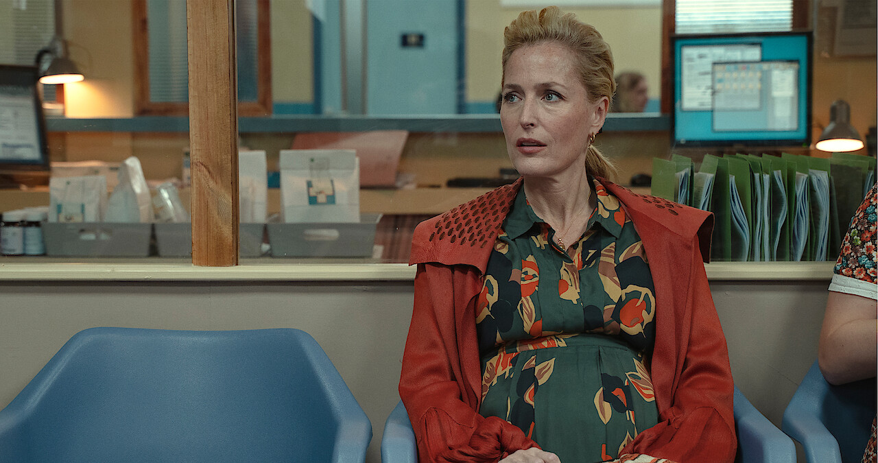 Gillian Anderson as Jean Milburn sits in the waiting room of a doctor's office while pregnant in Season 3 of ‘Sex Education.’